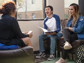 A group of friends (2 females, 1 male) sitting together, chatting and having a great time at Unity Hall.